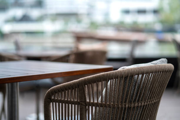 rattan wicker material fininshing dining table in cafe patio with blur outdoor garden